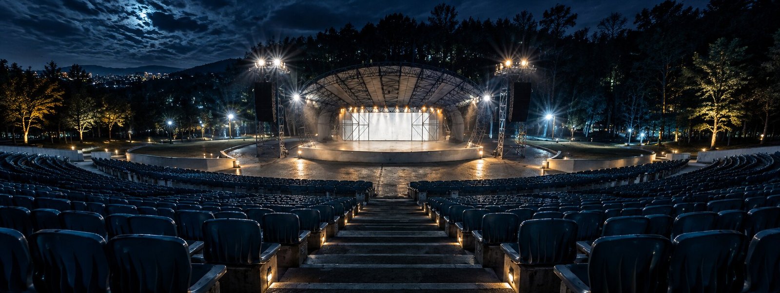 An empty open-air stage at night, lights on, before the show